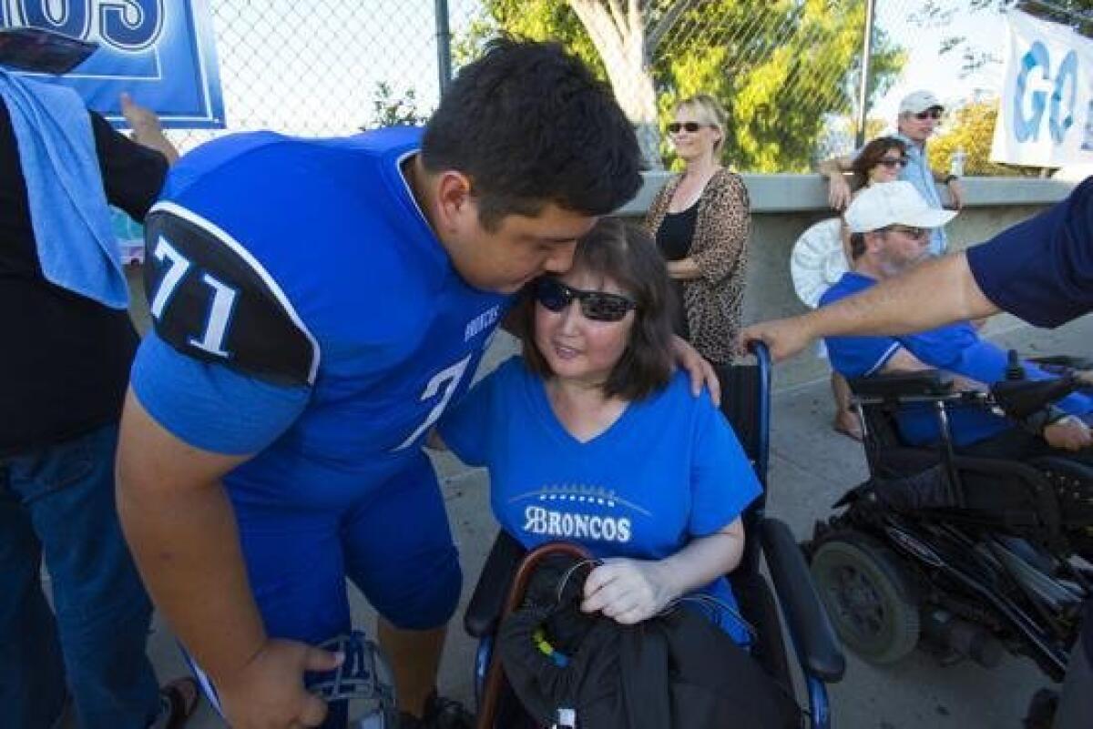 Evan Blakeney visits his mother, Debbie, in the stands at the Rancho Bernardo-San Pasqual game Friday night. Debbie has been fighting mucosal melanoma and the chance to see her son play football has been a dream of hers.