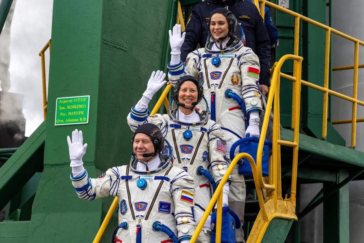 NASA astronaut Tracy Dyson, center, Oleg Novitsky of Roscosmos, bottom, and Marina Vasilevskaya of Belarus wave.