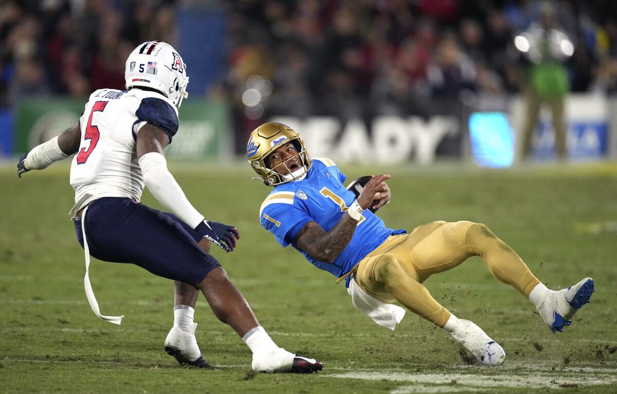 UCLA quarterback Dorian Thompson-Robinson, right, slips as he runs the ball while under pressure.