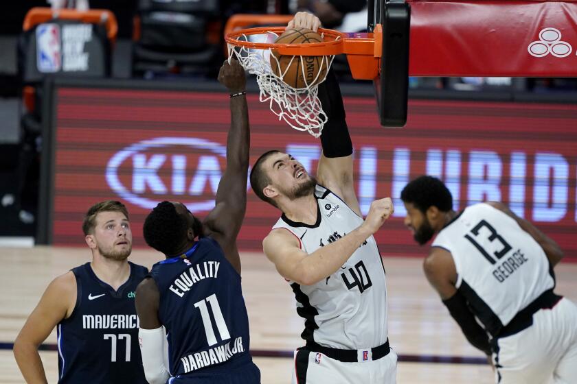 Los Angeles Clippers' Ivica Zubac (40) dinks on Dallas Mavericks' Tim Hardaway Jr. (11) during the first half of an NBA basketball game Thursday, Aug. 6, 2020 in Lake Buena Vista, Fla. Mavericks' Luka Doncic (77) looks on during the play. (AP Photo/Ashley Landis, Pool)