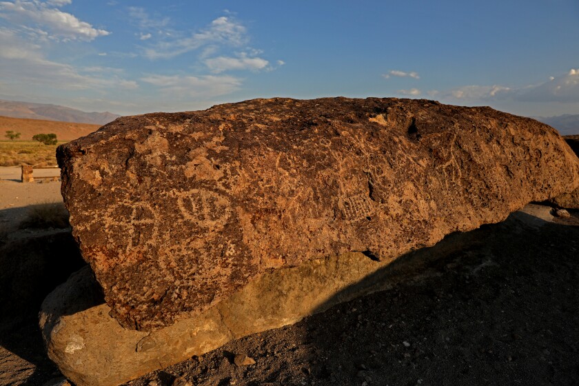 Etchings are seen on a large rock.