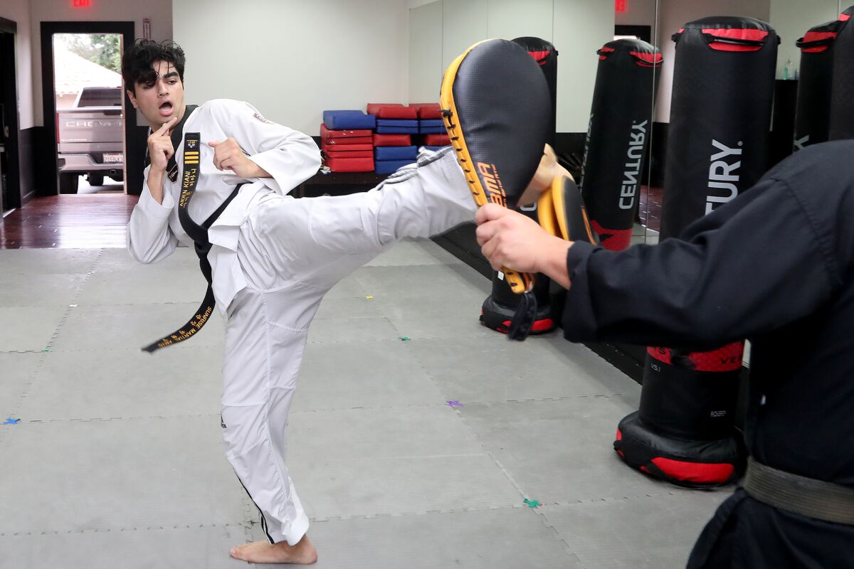 Sage Hill School senior Aiden Kiani, 17, practices kicking with his master, John Seock.