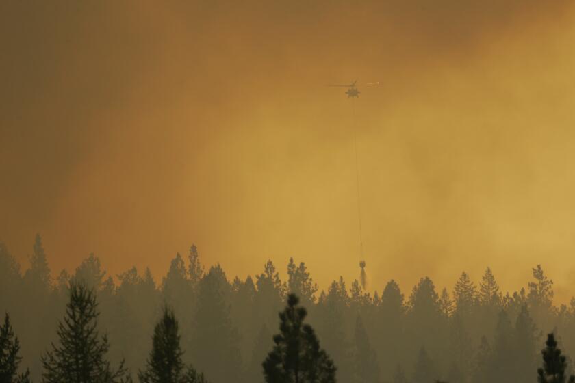 A helicopter makes a water bucket drop on a wildfire near Omak, Wash. Fires continue to rage across Washington state.