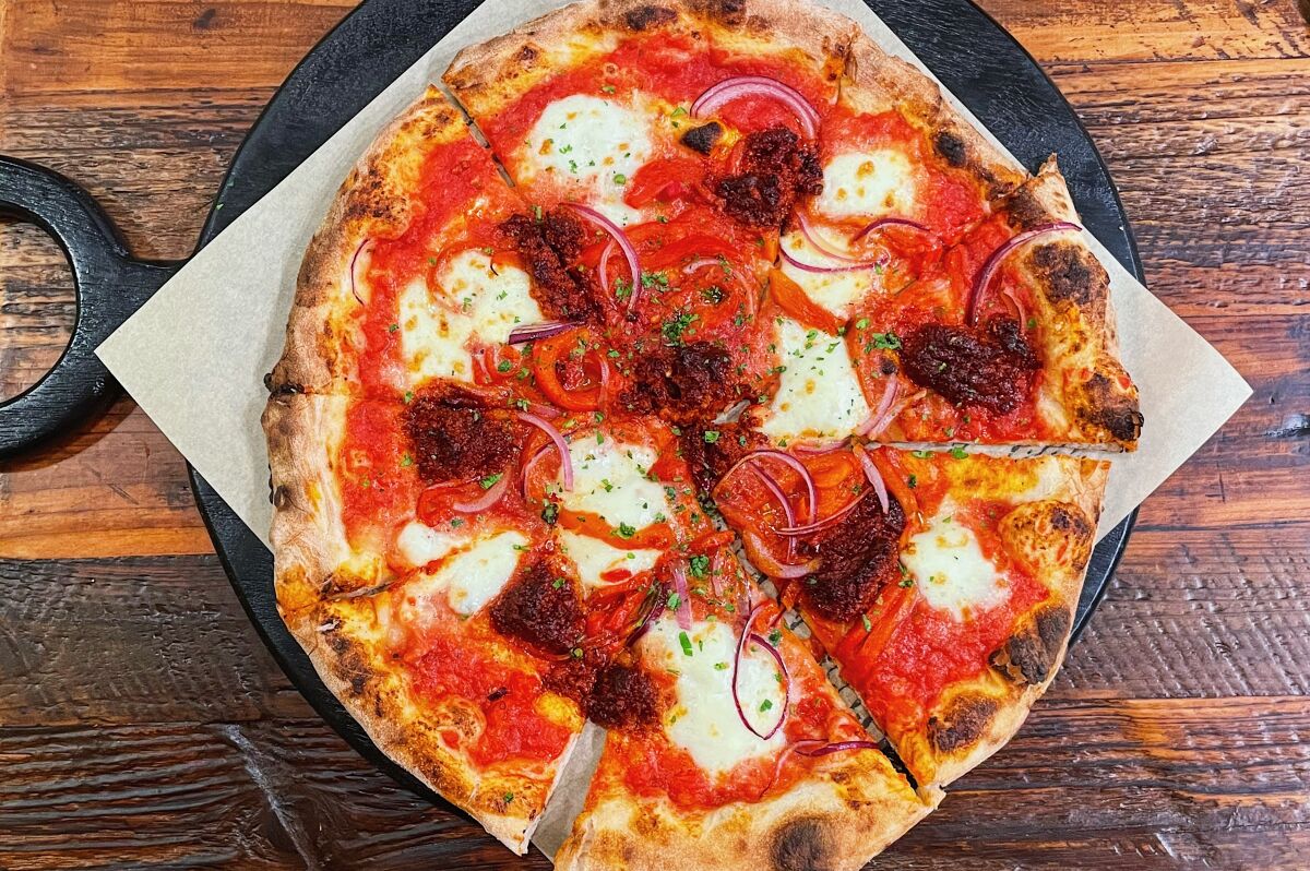 An overhead photo of a pizza from Little Goat Pizza House topped with 'nduja and roasted red peppers.