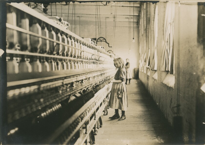 A historic photo of a young girl working in a cotton mill