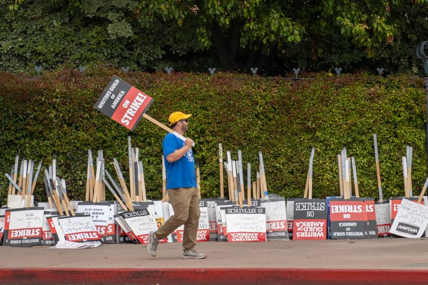 LOS ANGELES, CA - JUNE 06: A picketer walks past strike signs at the Walt Disney Studios in Burbank, CA on Tuesday, June 6, 2023 as the Writers Guild of America strike enters the sixth week. The Directors Guild of America recently signed a new contract and the screen actors guild SAG-AFTRA has authorized a strike at the end of the month if they cannot come to terms with the studios. (Myung J. Chun / Los Angeles Times)