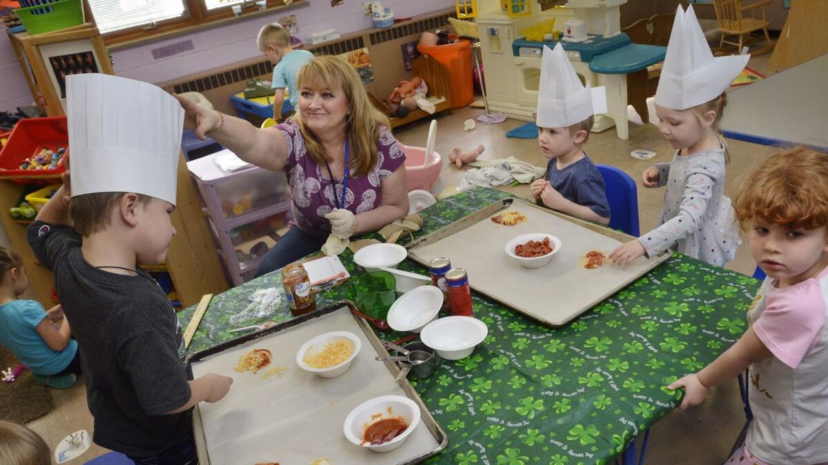 Teacher Debbie Kukuris-Milford helps preschoolers adjust their chef's hats and make pizzas at Westminster Preschool in Marion, Ind. (Jeff Morehead / Associated Press)