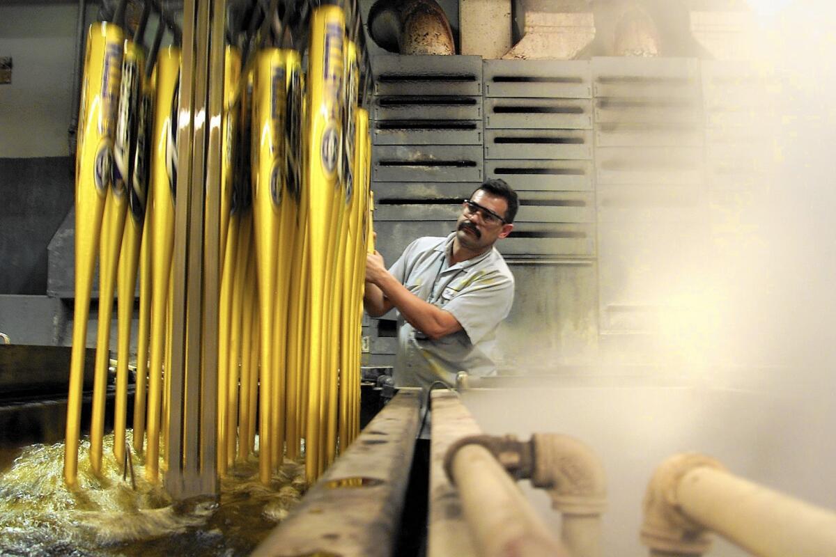 An Easton worker lifts aluminum basebal bats out of a gold anodizing solution at the company's Van Nuys manufacturing plant in 2002.