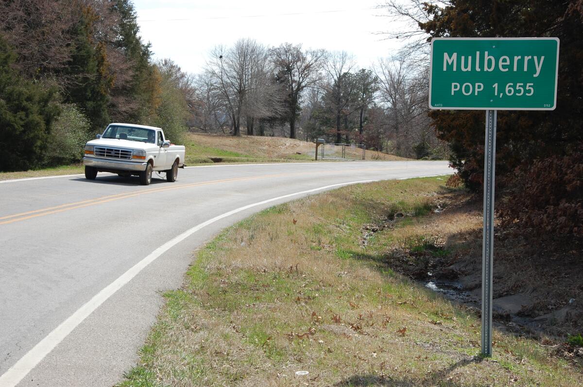 Truck driving on highway near sign for Mulberry, Ark.