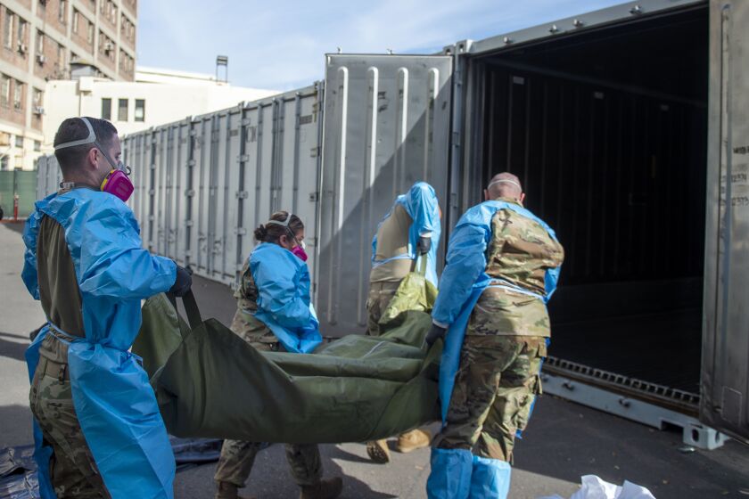 FILE - In this Jan. 12, 2021 photo provided by the Los Angeles County Department of Medical Examiner-Coroner, National Guard members assisting with processing COVID-19 deaths, placing them into temporary storage at the medical examiner-coroner's office in Los Angeles. The seven-day rolling average of daily deaths is rising in 30 states and the District of Columbia, and on Monday, Jan 18, 2021, the U.S. was approaching 398,000, according to data collected by Johns Hopkins University, by far the highest of any country in the world. (Los Angeles County Department of Medical Examiner-Coroner via AP, File)