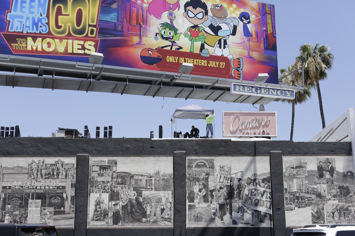 A movie billboard looms over a mural on the side of Canter's on Fairfax Avenue.