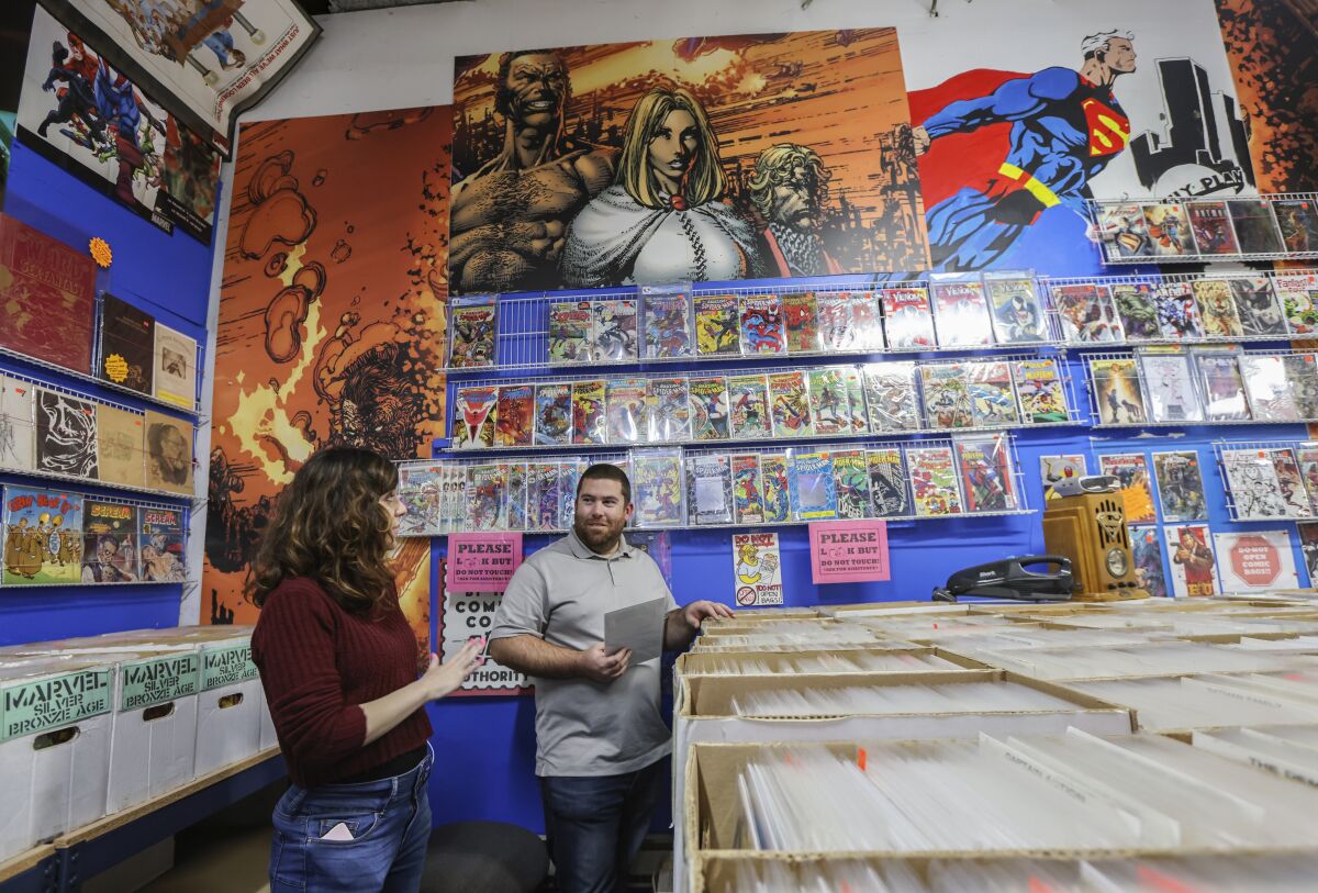A woman, left, and a man talk in a comic book store
