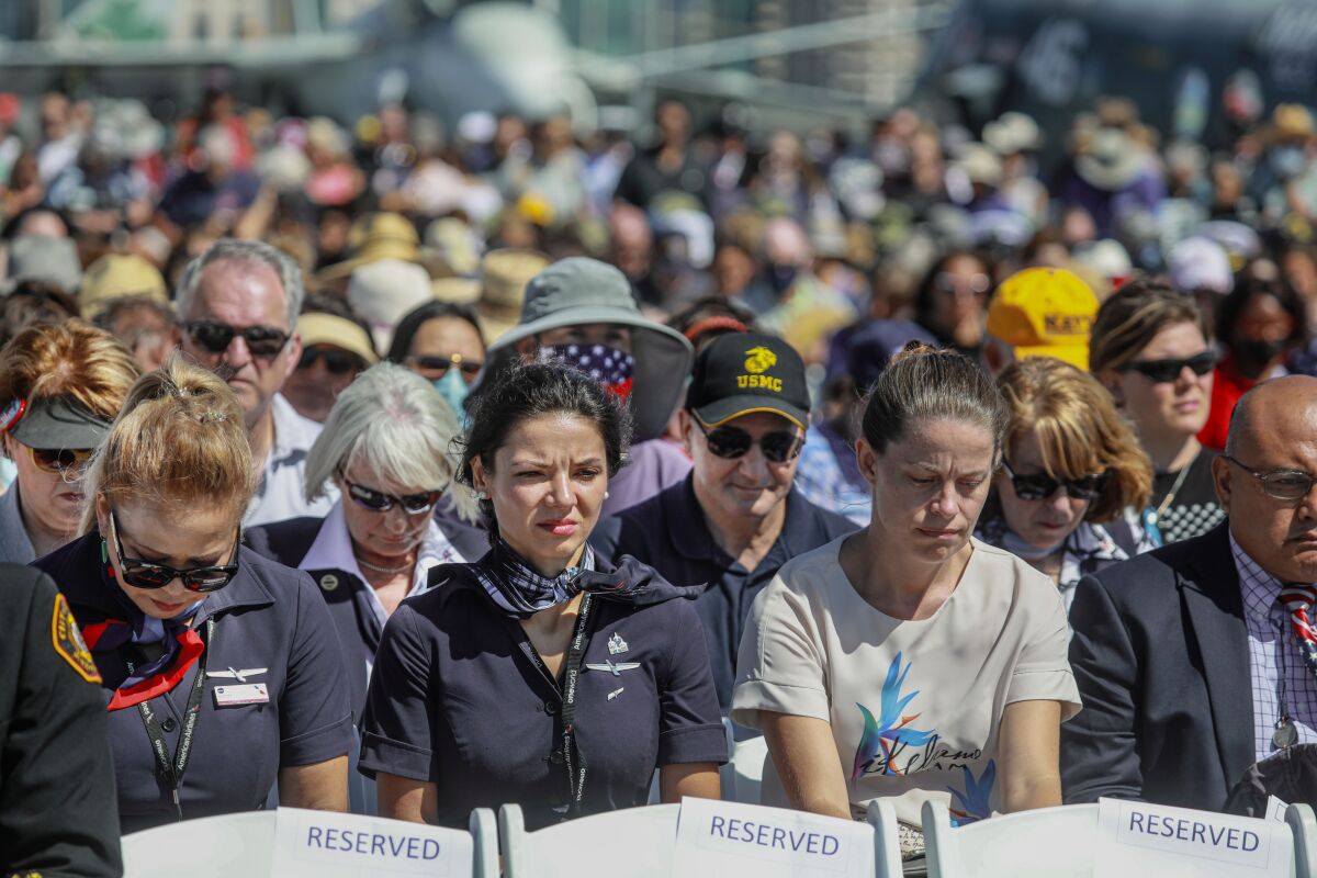 Seated attendees bow their heads at a 9/11 memorial on the USS Midway.