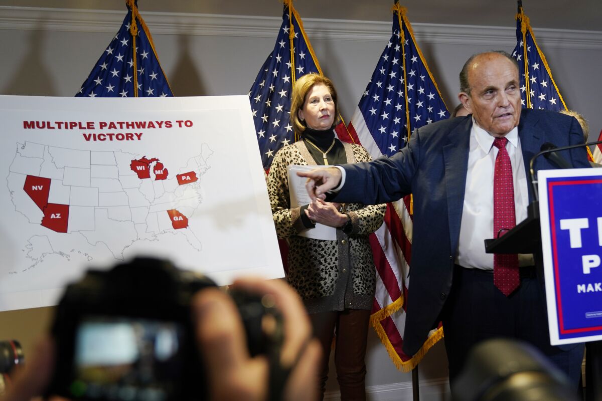 Rudy Giuliani points to a map titled Multiple pathways to victory with some close states won by Biden highlighted in red