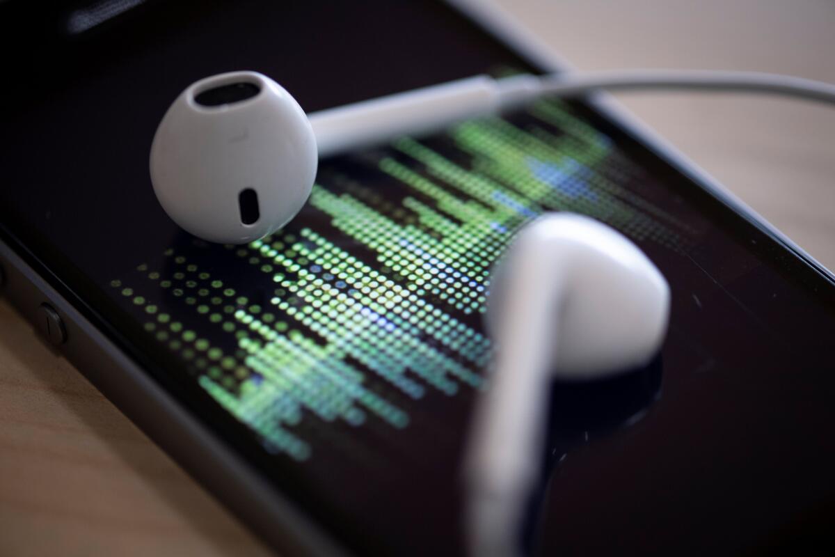 Closeup of earphones lying on a smartphone as an audio podcast is played. 