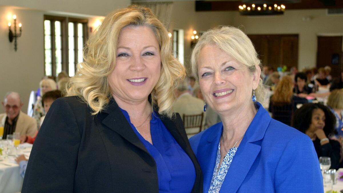 Welcoming members and guests to their Spring Social are La Providencia Guild President Sue Meckley, right, and Cari Pelayo, who served as the day's mistress of ceremonies.