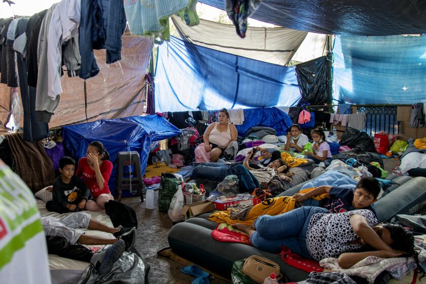 REYNOSA, MEXICO - DECEMBER 6, 2021: Asylum-seeker Maria Jacinto Gomez, 27, of Guatemala, right, sleeps on an air mattress with her 11 year-old son nearby in the crowded gazebo filled with migrants at the Plaza Las Americas migrant tent camp which currently holds 2,000 migrants on December 6, 2021 in Reynosa, Mexico. Gomez and her son have been there for 5 months. Felicia Rangel-Samponaro runs her non-profit Sidewalk School at the tent camp so the children of migrants from Central America and Haiti can learn English and other studies.(Gina Ferazzi / Los Angeles Times)