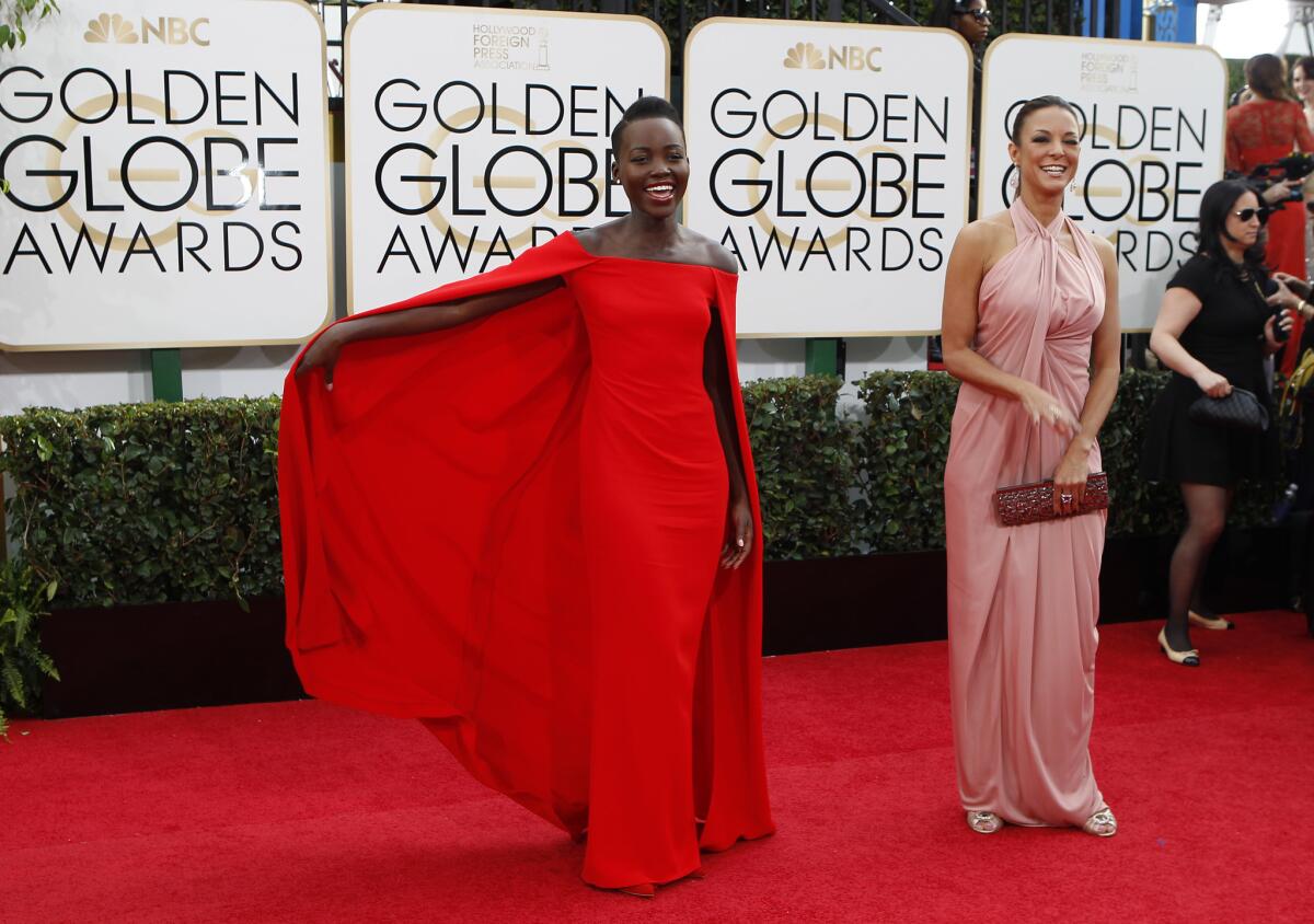Actress Lupita Nyong'o in a red cape dress by Ralph Lauren.