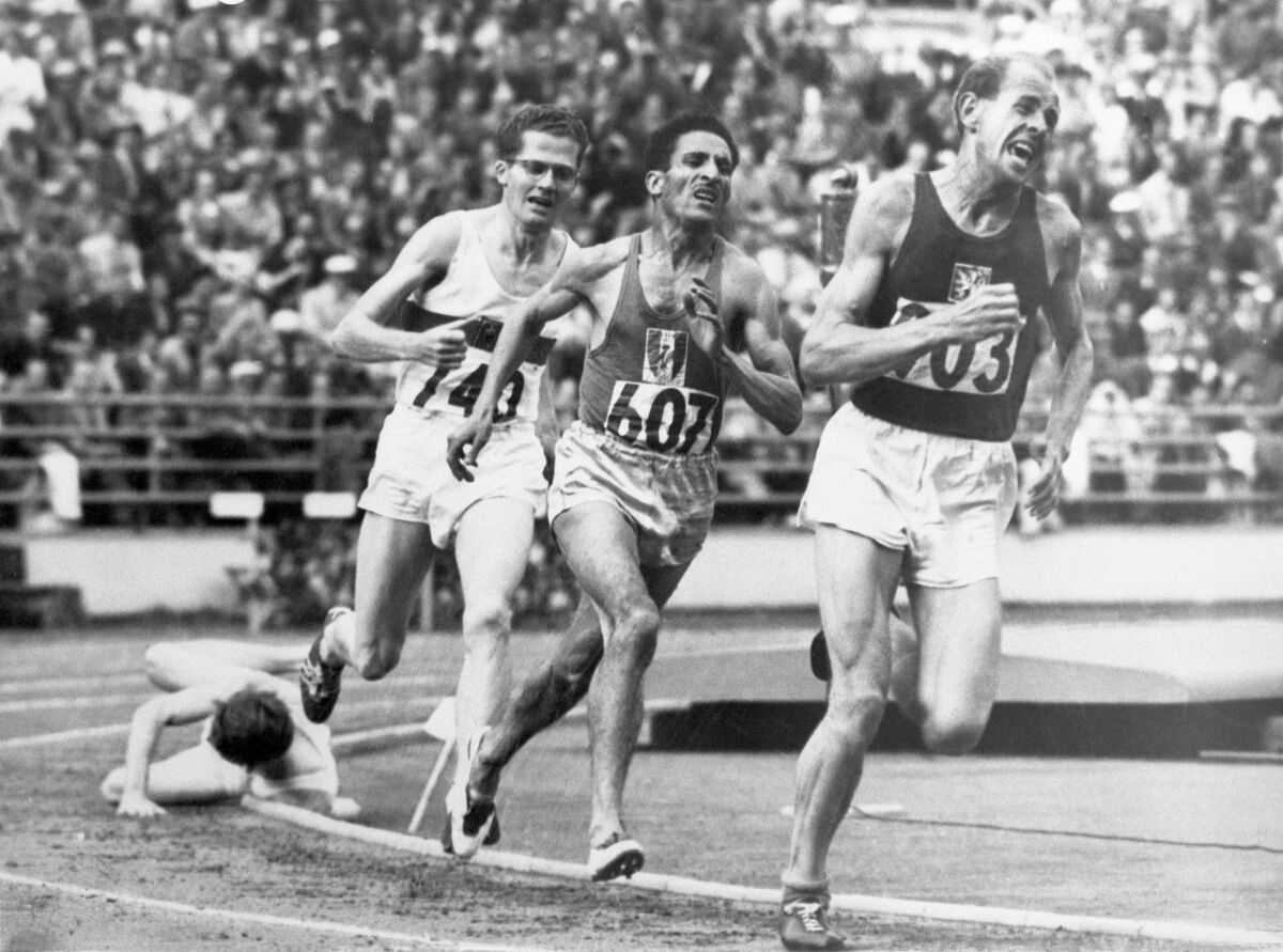 FILE - In this July 24, 1952, file photo, British athlete Christopher "Chris" Chataway falls as Emil Zatopek of Czechoslovakia, followed by Alain Mimoun of France and German bronze medal winner Herbert Schade, leads near the end of the Men's final 5000 meter race at the Summer Olympic Games on in Helsinki, Finland. (AP Photo/File)