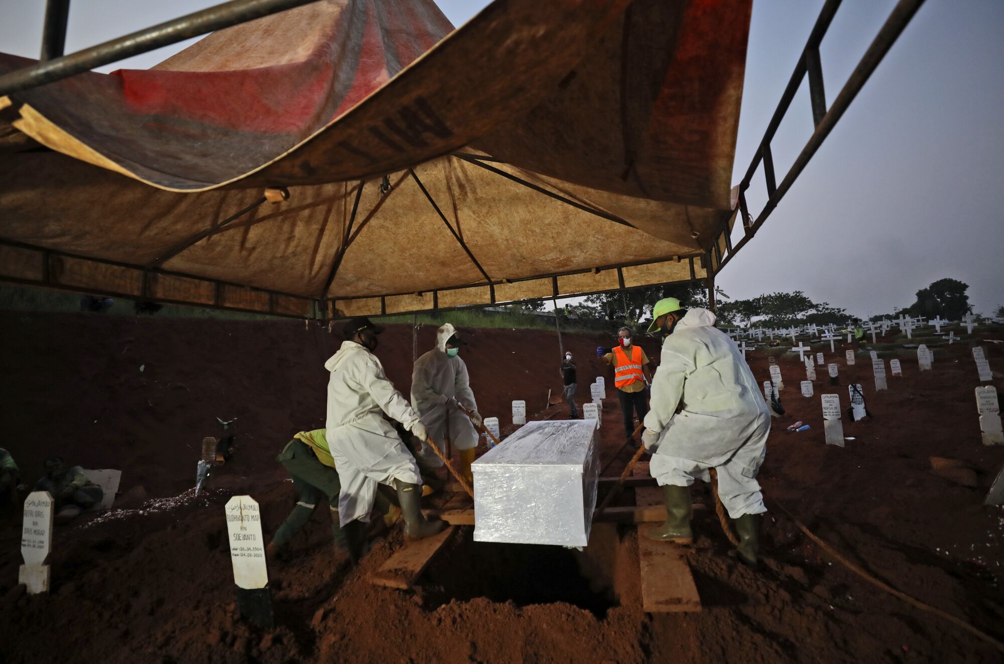 Workers lower a coffin containing the body of a suspected COVID-19 victim into a grave at Pondok Ranggon cemetery.