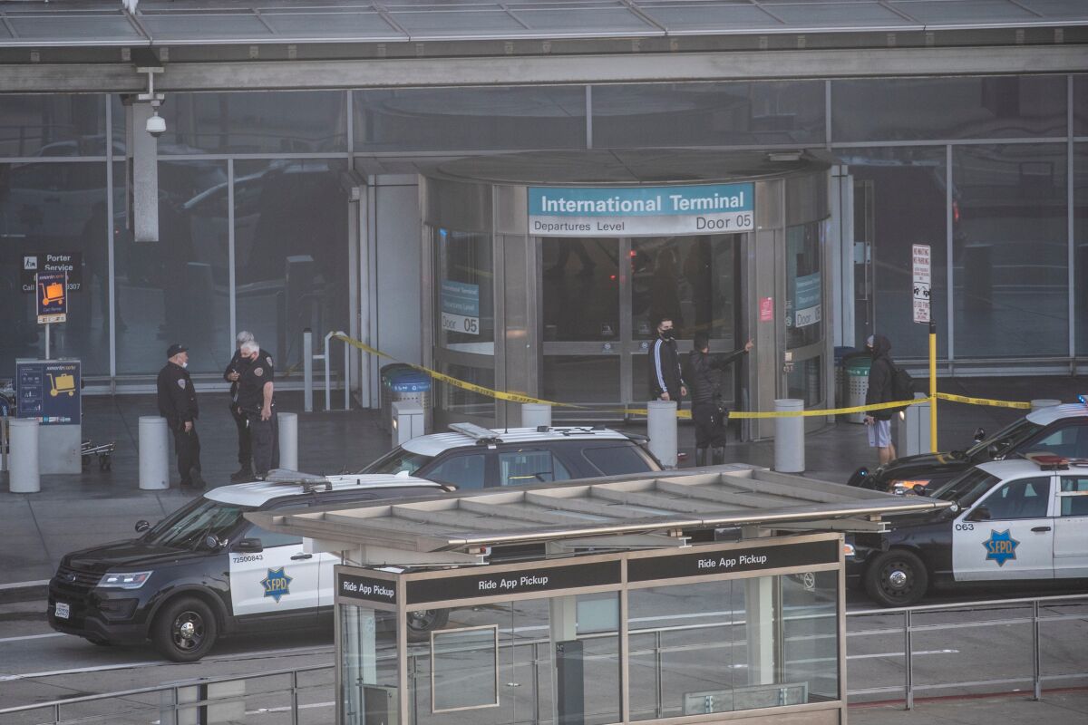 Police and yellow crime scene tape around an airport terminal entrance.