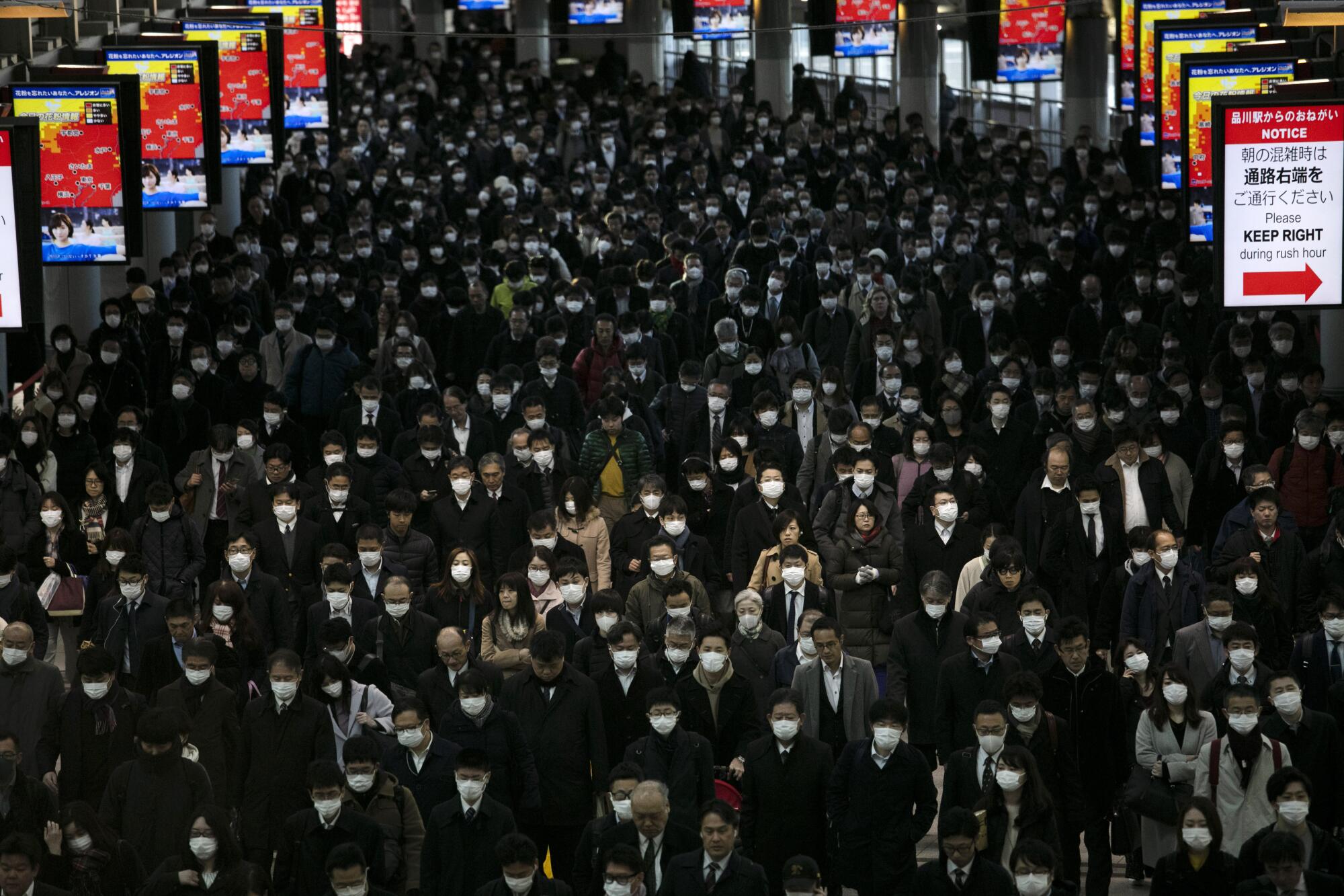 A large crowd of mask-wearing commuters 