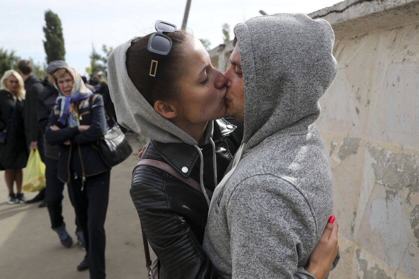 A Russian recruit and his wife kiss and hug each other outside a military recruitment center in Volgograd, Russia 