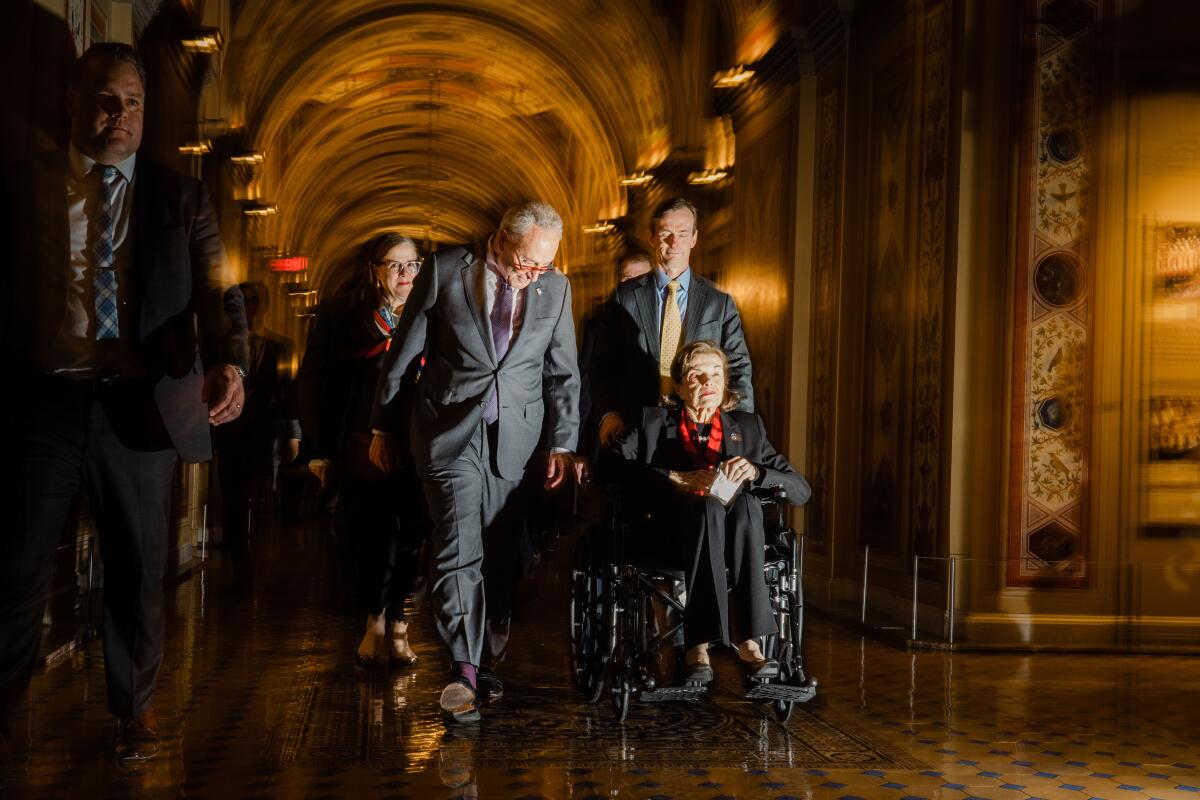 A woman is pushed in a wheelchair by a man while another man walks next to her.