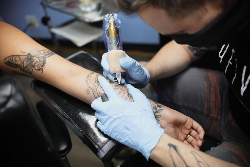 Eric Whitman works on a tattoo