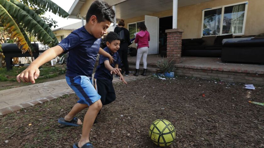 Axel Vasquez, 7, left, and his brother Neymar, 5, play in the frontyard of their home on Percy Street in Boyle Heights. Their yard has an elevated lead level, but it's not high enough to qualify for the state's priority list for cleanup.