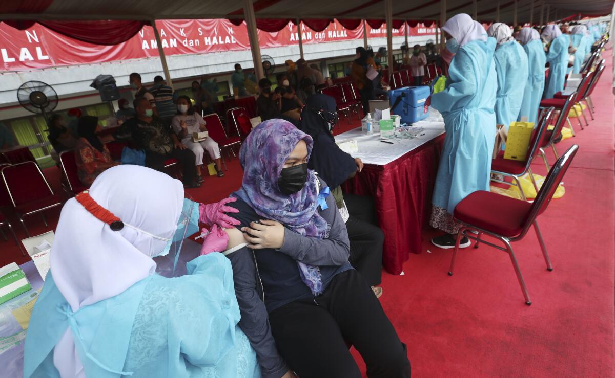 A woman receives a shot of the Sinovac vaccine for COVID-19 during a vaccination campaign at the Patriot Candrabhaga Stadium in Bekasi on the outskirts of Jakarta, Indonesia, Thursday, July 1, 2021.(AP Photo/Achmad Ibrahim)