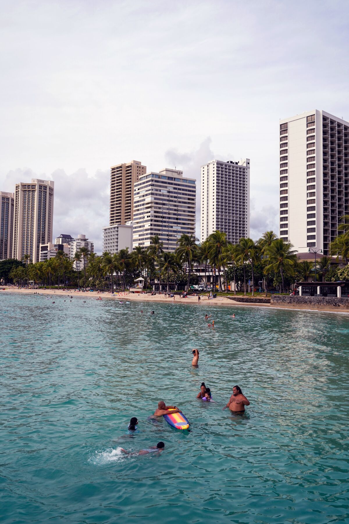 People wade in the waters off Waikiki Beach.