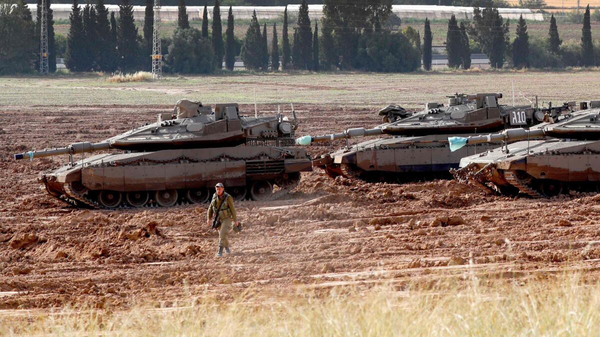 An Israeli soldier walks in front of Merkava tanks stationed in southern Israel, near the border with the Gaza Strip.