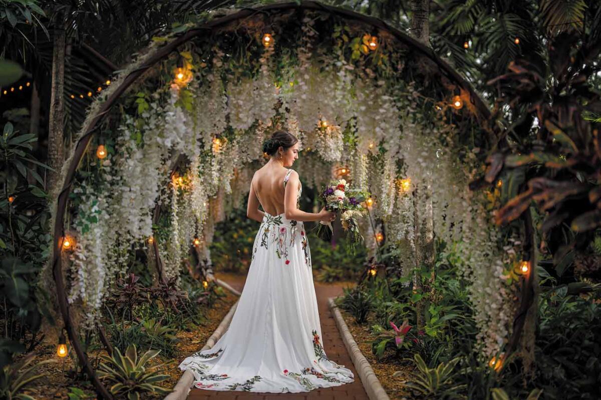 A bride stands in the floral tunnel at the Sanctuary wedding venue.