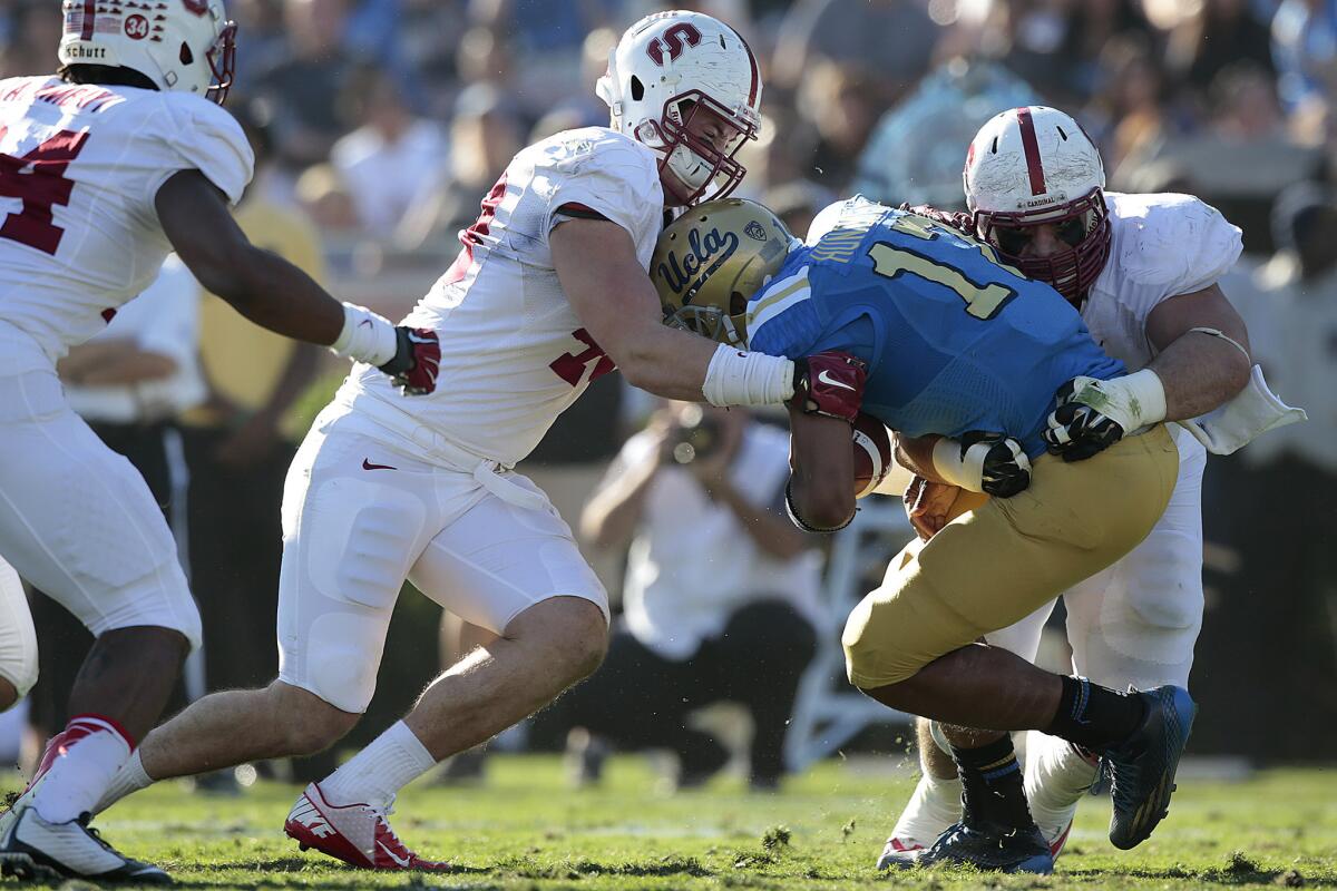 UCLA quarterback Brett Hundley is dragged down by Stanford linebacker Kevin Anderson, left, and defensive tackle David Parry in the second quarter of the Bruins' 31-10 loss to the Cardinal at the Rose Bowl.