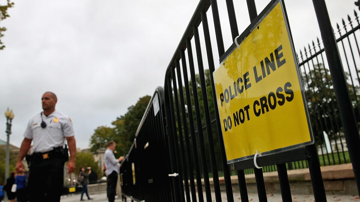 A Secret Service officer patrols near an added security fence outside the White House.