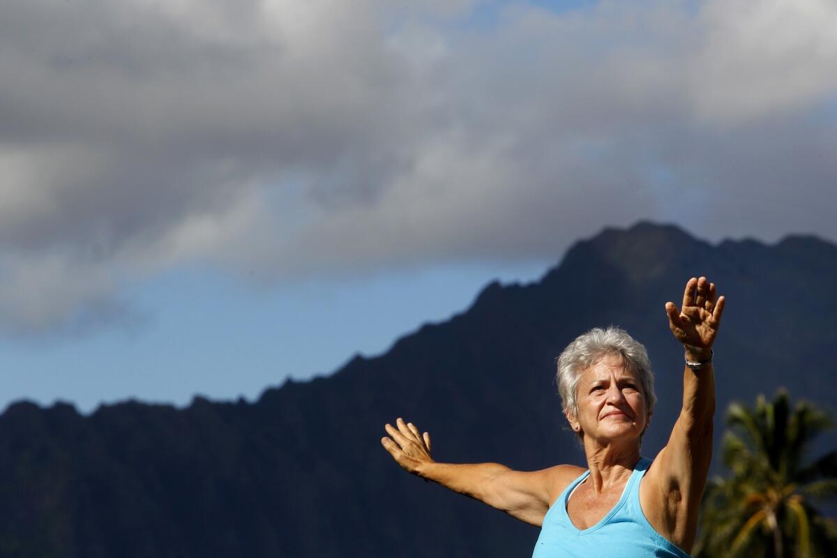 Myra Williams, a breast cancer survivor, demonstrates a yoga pose behind her home in Kailua, Hawaii. Williams, 64, has lived in Hawaii for 35 years.