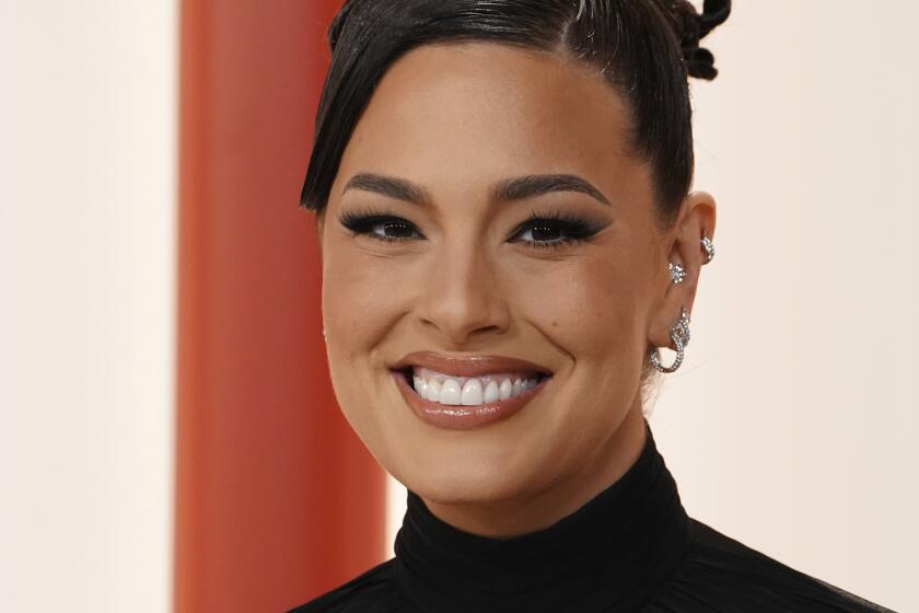 A woman with a braided bun in a black gown smiles