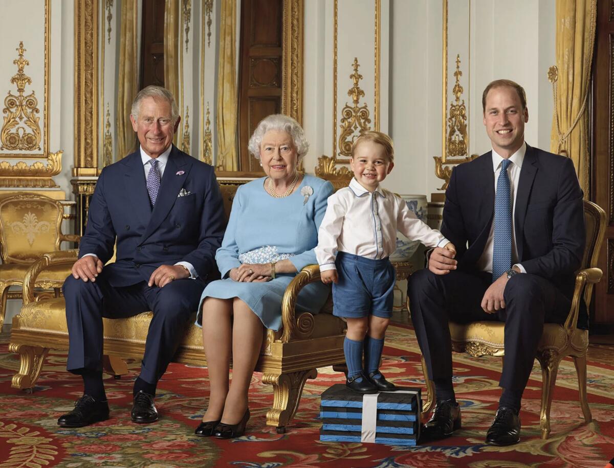 Queen Elizabeth II and Princes Charles and William sitting as Prince George stands on a stack of books for a group portrait