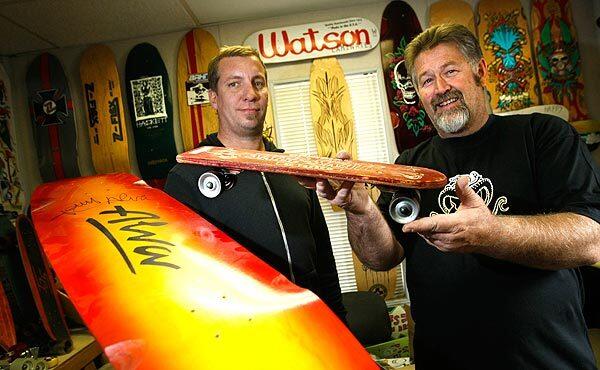 Watson Laminates owner Tod Swank, left, poses with longtime employee Jim Johnson, who holds a 1950s-era plywood deck made with steel wheels.