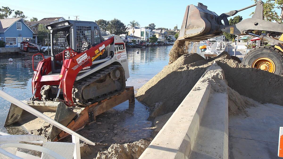 Crews with the city of Newport Beach dump sand along the Grand Canal on Balboa Island in 2015 in an attempt to reinforce old sea walls.