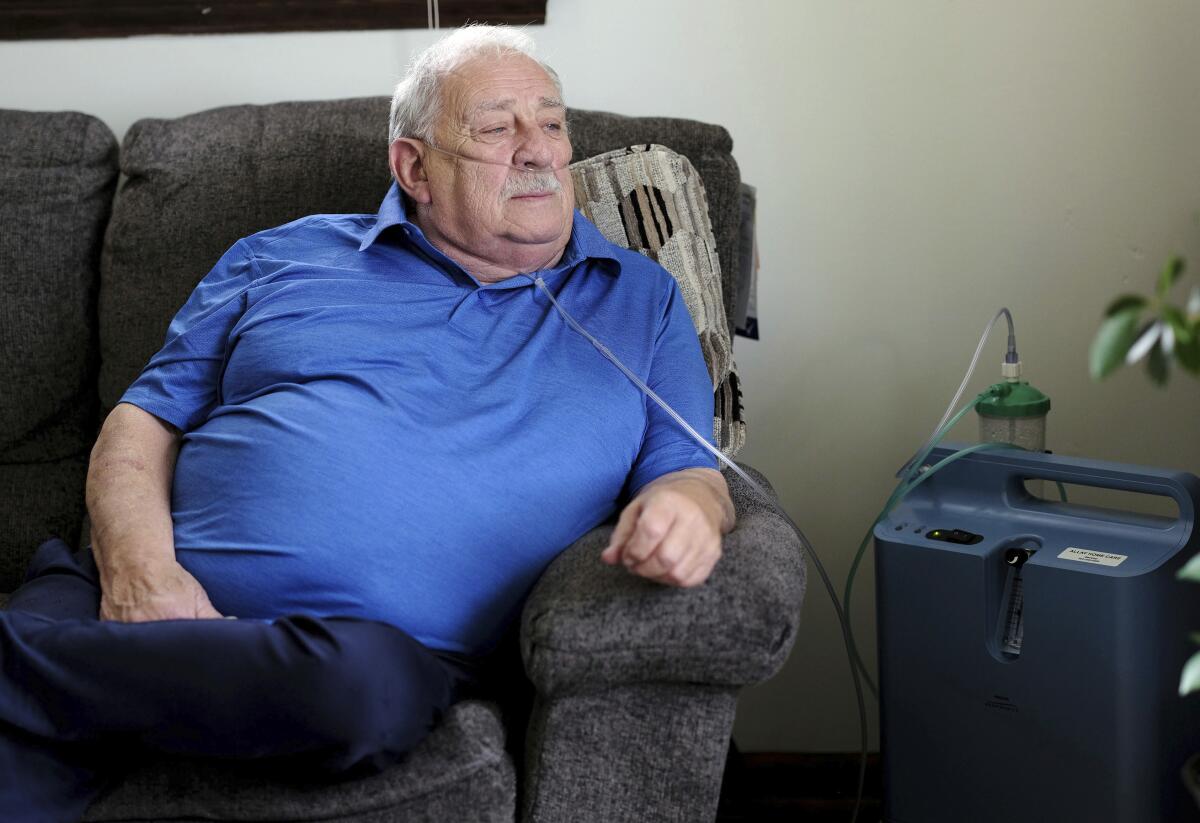 Retired coal miner James Bounds, using an oxygen machine, sits on a couch at his home in Oak Hill, W.Va.