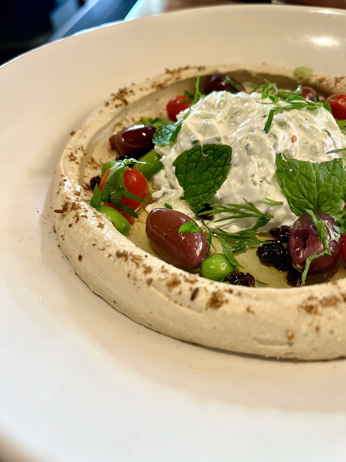 Hummus topped with tzatziki, dill, olives and served with crispy pita at Joey Newport Beach.