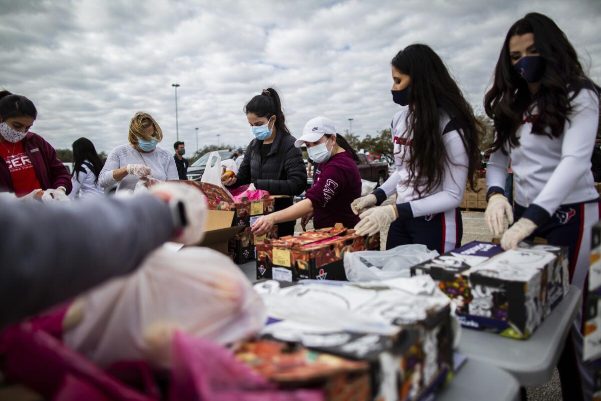 People in masks and gloves fill boxes with food.