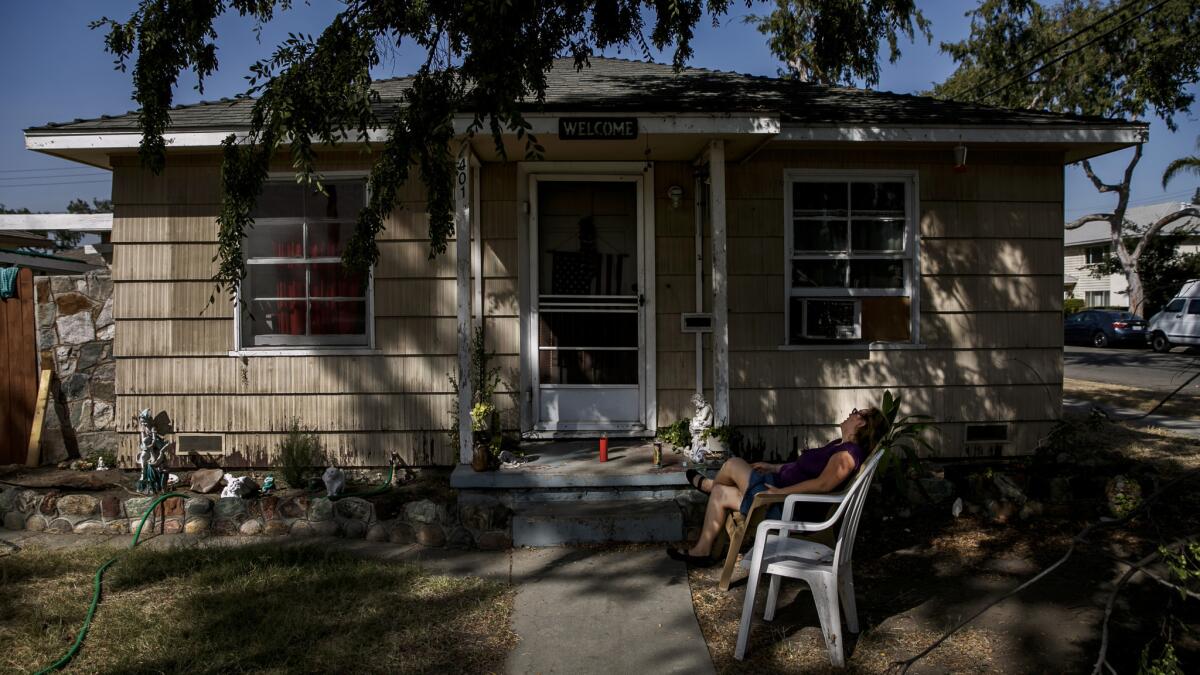 A family friend sits outside the house where police found three people dead.