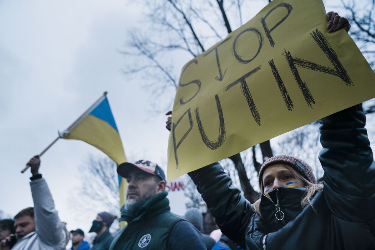 People hold Ukraine flags and a sign reading "Stop Putin."
