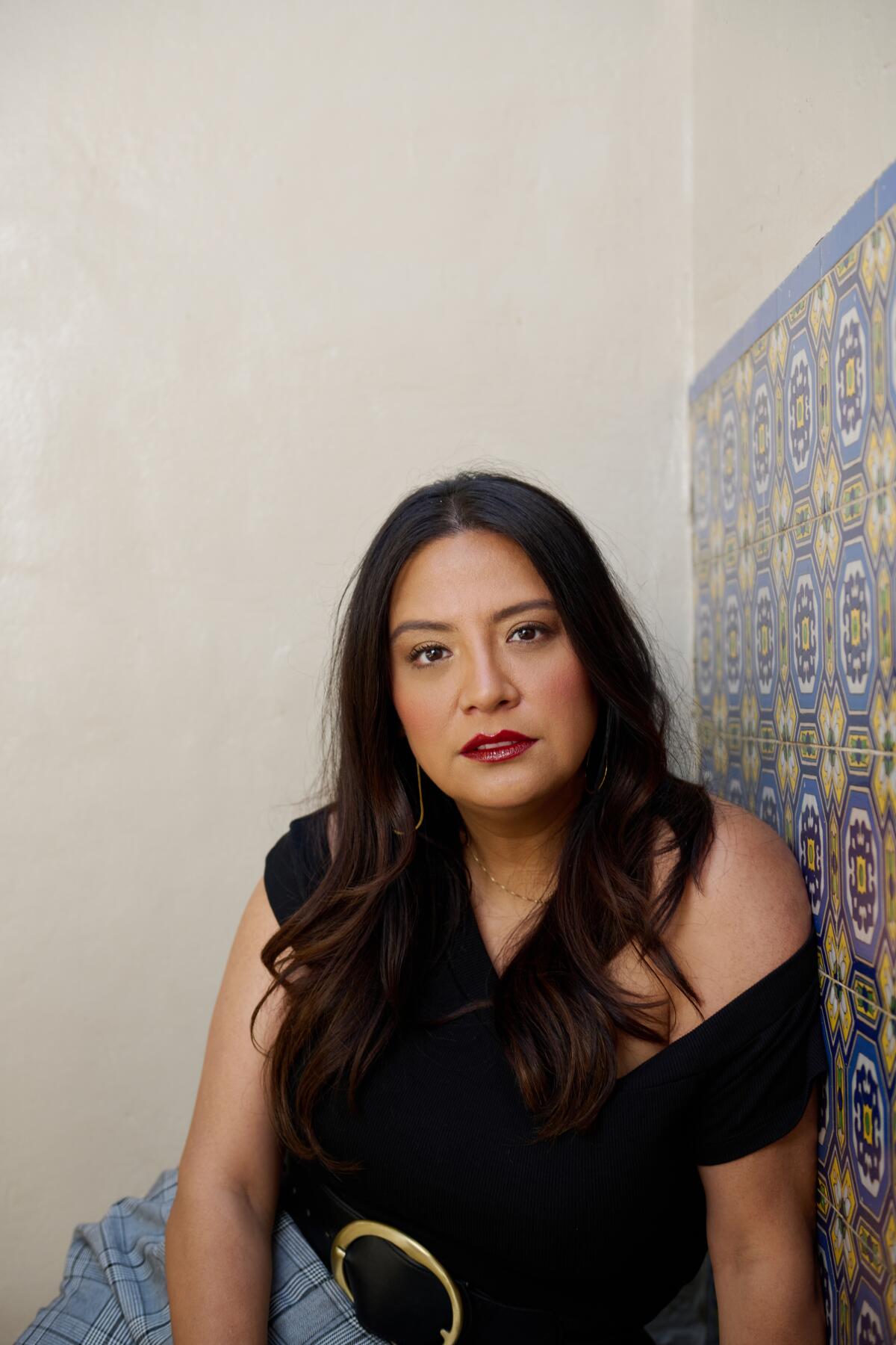 Comedian Cristela Alonzo sitting against a wall.