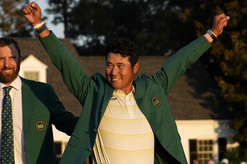 Hideki Matsuyama, of Japan, puts on the champion's green jacket after winning the Masters golf tournament.