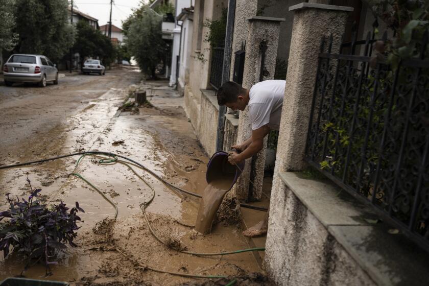 A man clears mud water from the yard of his house following floods at the town of Agria near the city of Volos, Greece, Thursday, Sept. 28, 2023. A second powerful storm in less than a month hammered parts of central Greece Thursday, sweeping away roads, smashing bridges and flooding thousands of homes. (AP Photo/Petros Giannakouris)
