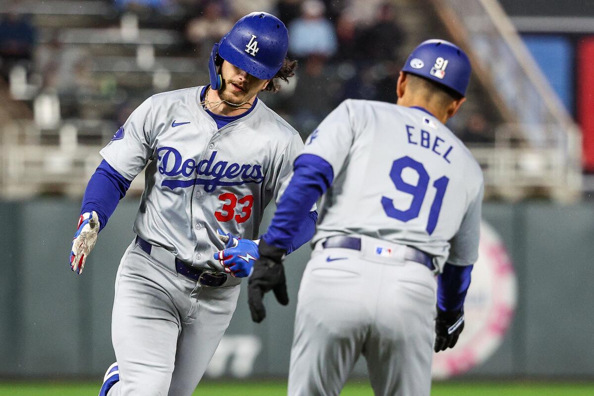James Outman is congratulated by Dodgers third base coach Dino Ebel after hitting a solo home run against the Twins.